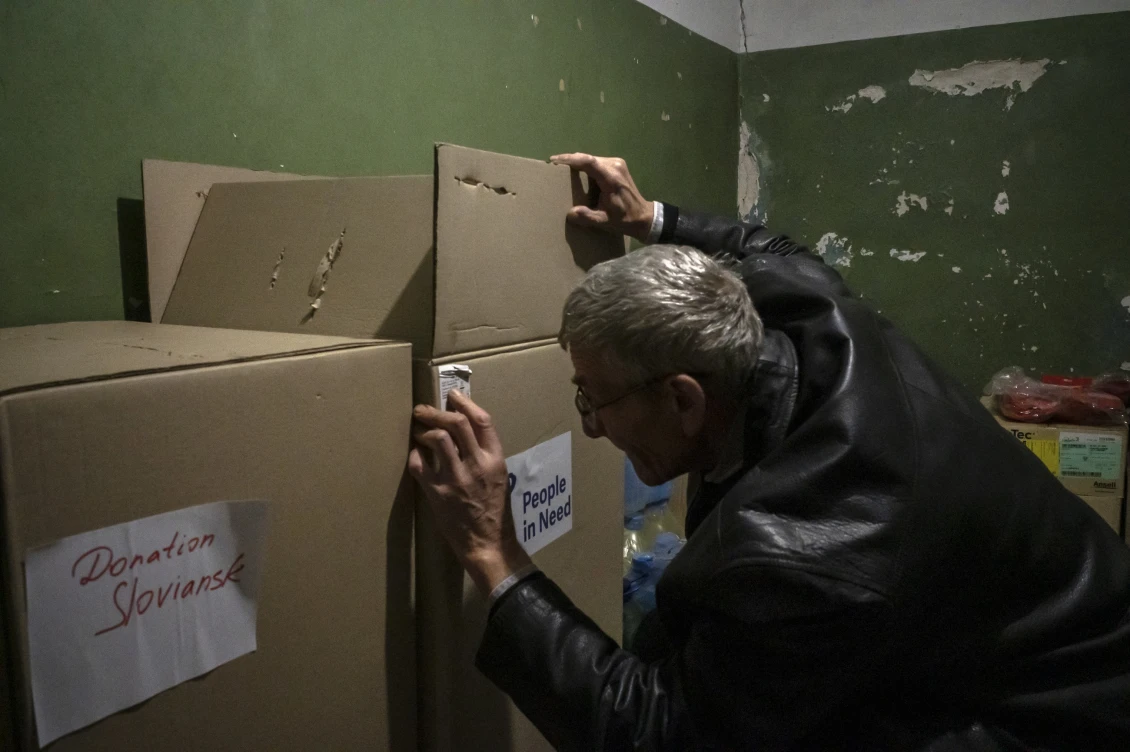 Співробітник оглядає коробки з гуманітарною допомогою. 