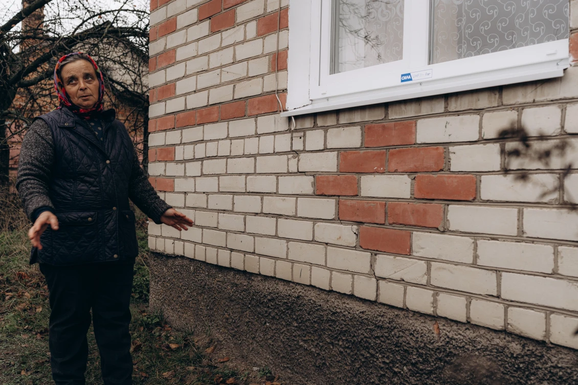 Liubov shows one of the seven windows we installed and the cracks that appeared on the house after the explosions. 