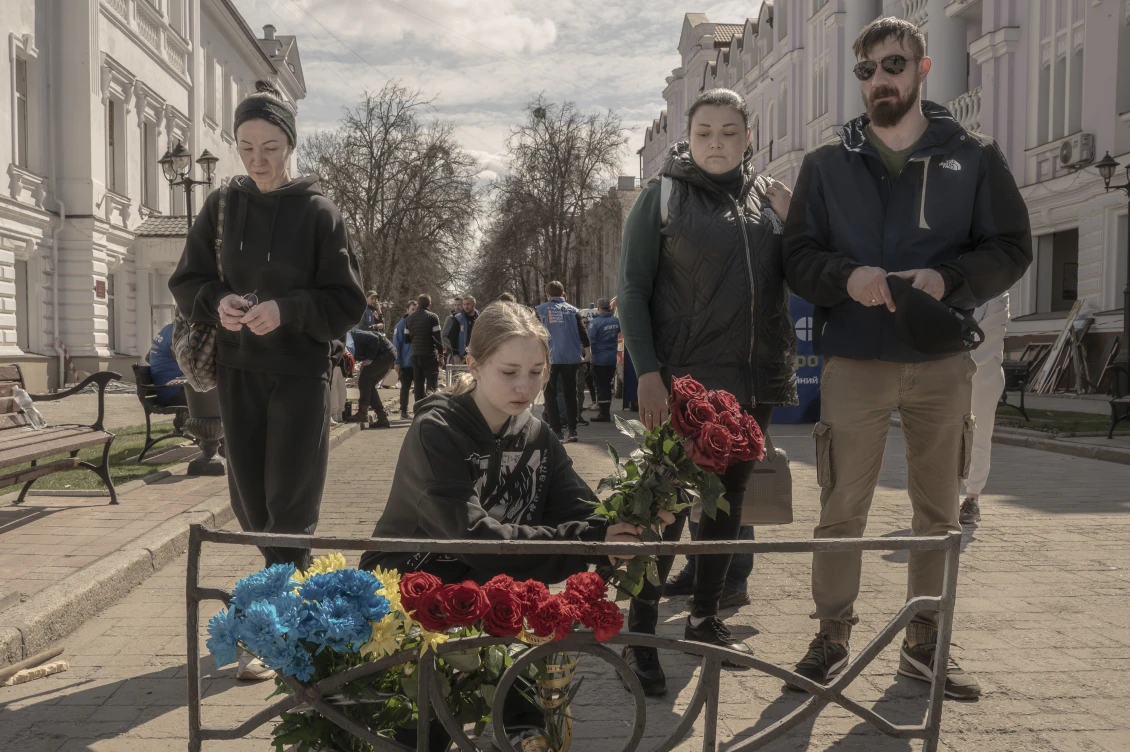 Жителі міста покладають квіти до імпровізованого вівтаря, щоб вшанувати пам'ять жертв російської ракетної атаки. 
