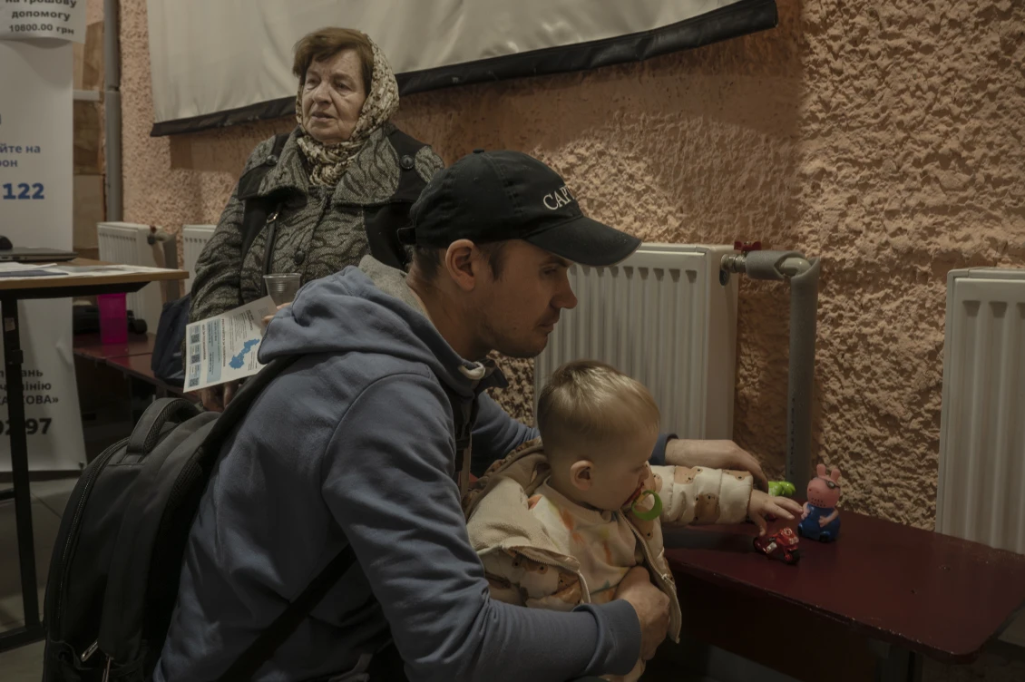 Батько з дитиною і літня жінка чекають на допомогу в центрі, створеному міською адміністрацією для підтримки постраждалих від атаки. 
