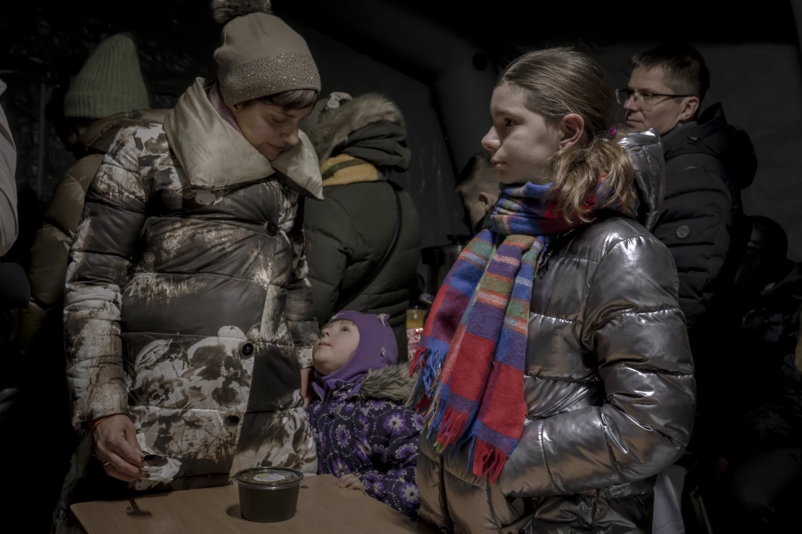 Daria, 33, and her daughters Vira and Serafima stand at an invincibility point near their apartment building on the outskirts of Kyiv, where they came to receive warm soup and shelter from the cold